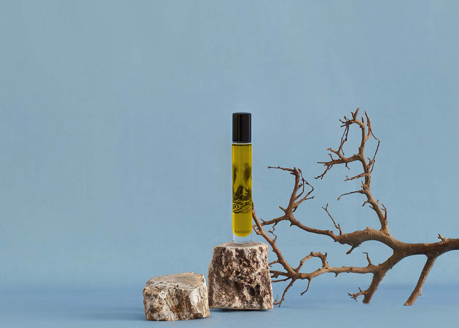Colpo dell'onda scented oil for a moment of energy featured in a scene with rocks, and branches.